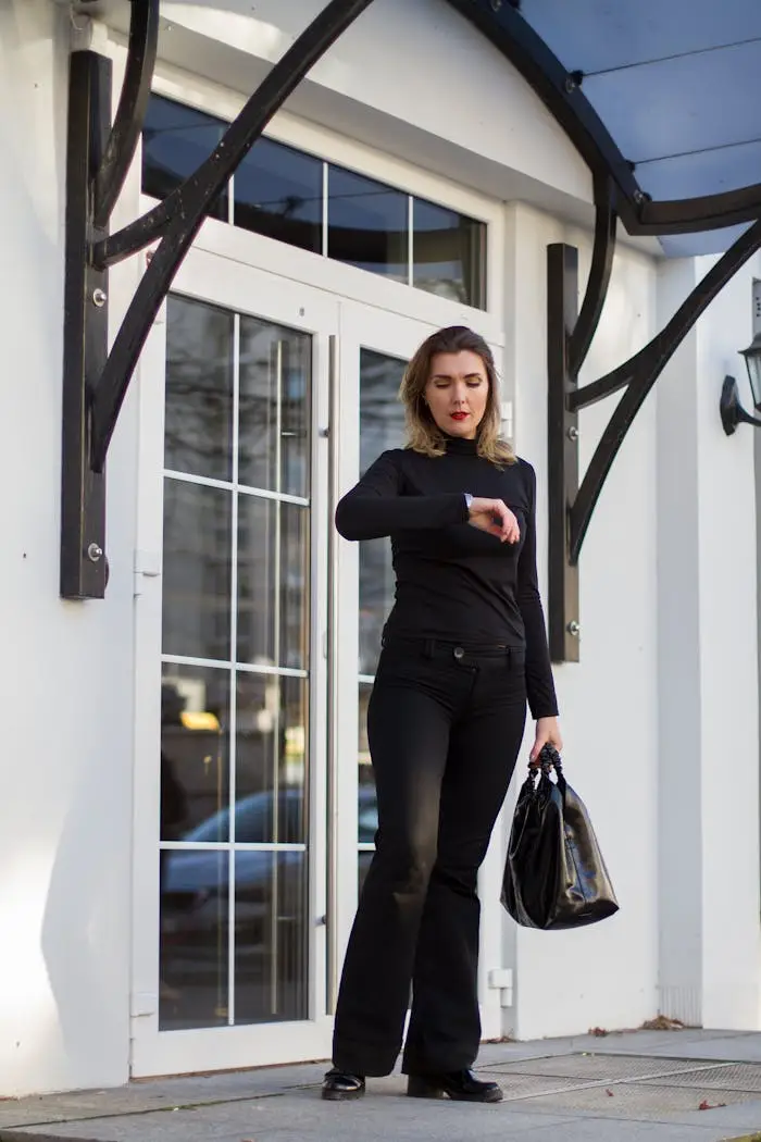 Stylish professional woman checks time outside modern building, emphasizing punctuality and elegance.