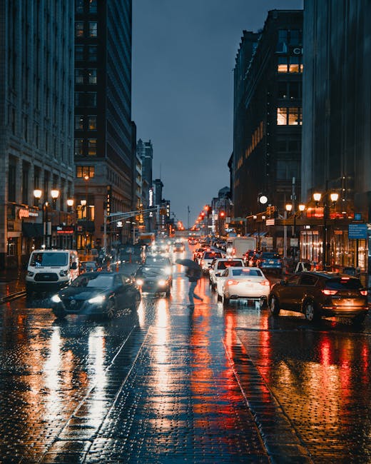 A vibrant night scene of urban traffic with illuminated city buildings and reflections on wet streets.
